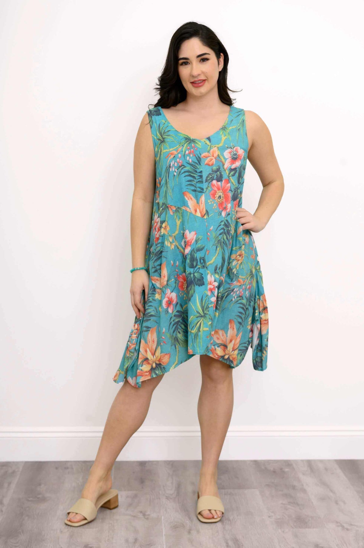 Woman posing legs apart in turquoise floral print dress with asymmetrical hemline
