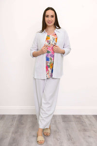 Woman in white pants and shirt, floral top underneath, standing straight