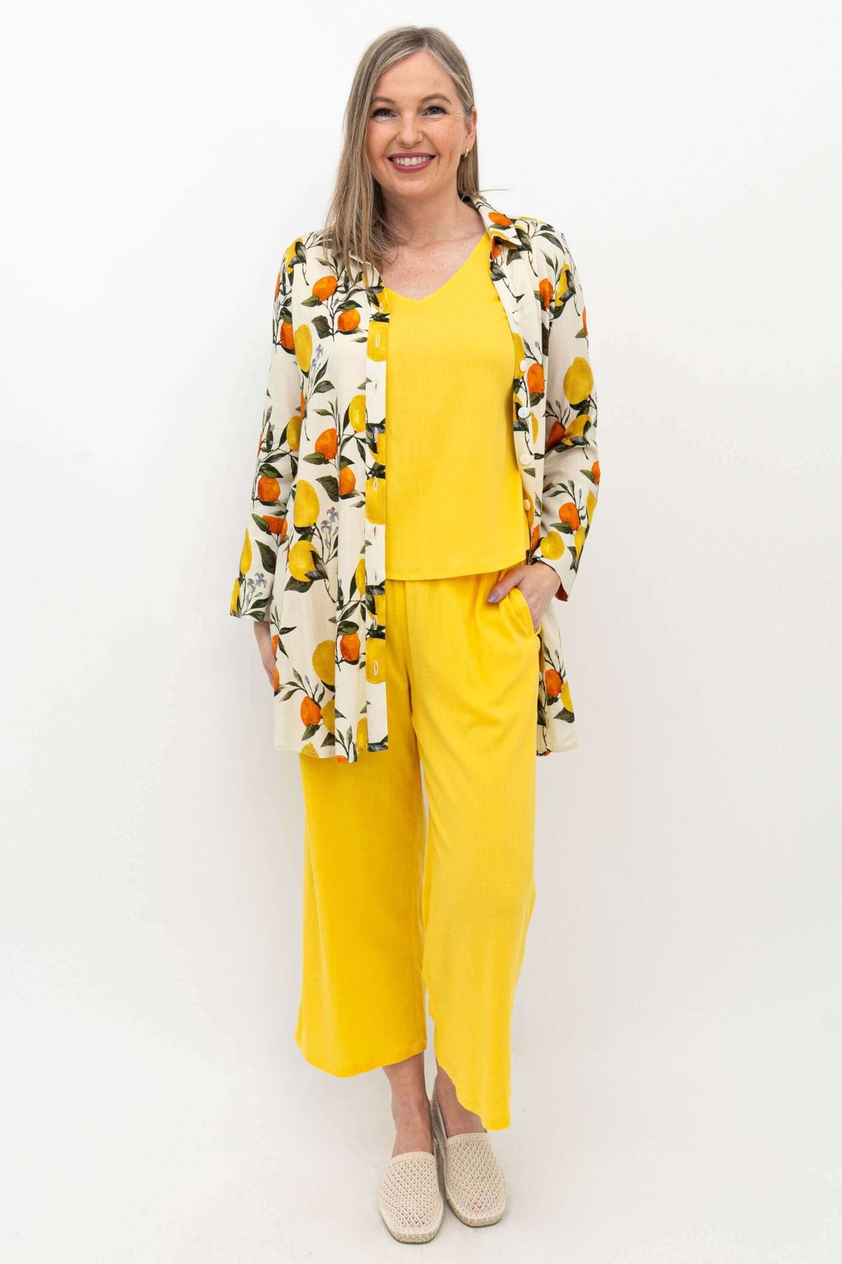 Woman styled in yellow cropped capris, matching top, and a lemon print shirt