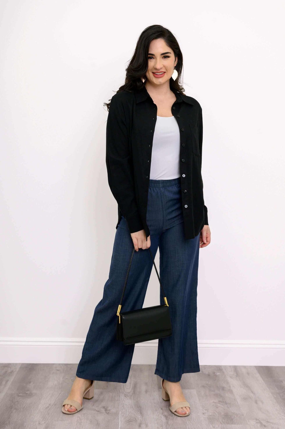 Woman styling Parker wide leg tencel pants with a white top, black shirt, and handbag