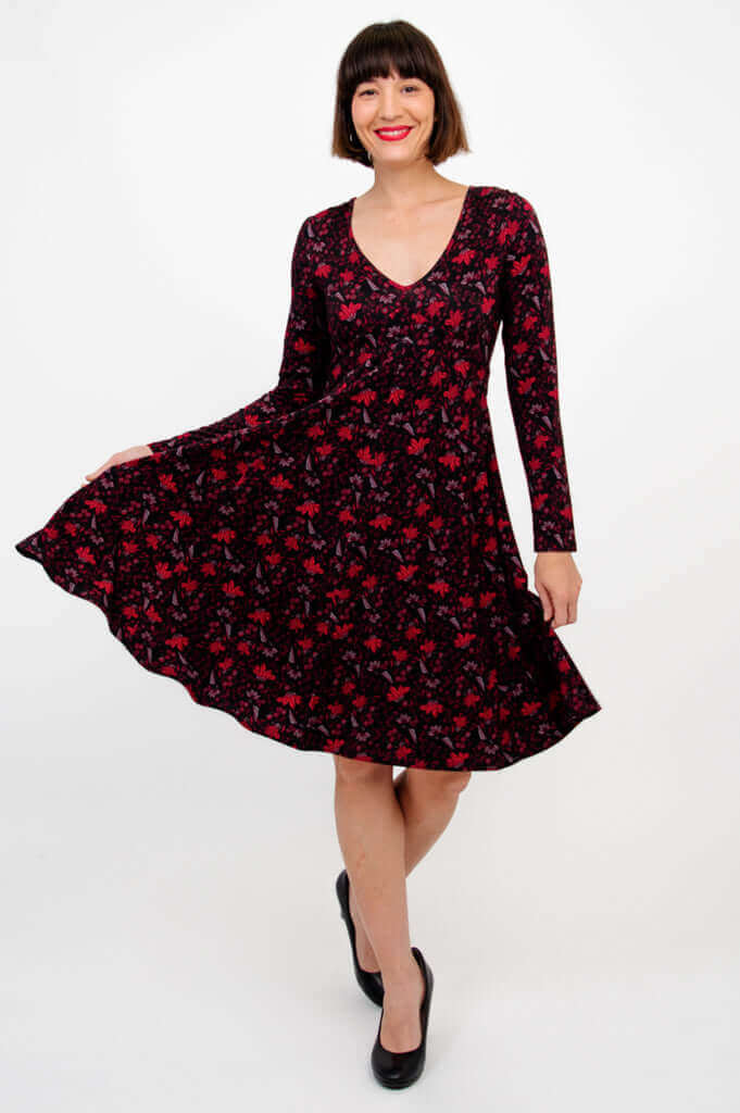 Woman twirling in black and red floral dress with long sleeves, front angle