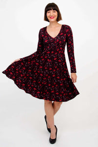 Woman twirling in black and red floral dress with long sleeves, front angle