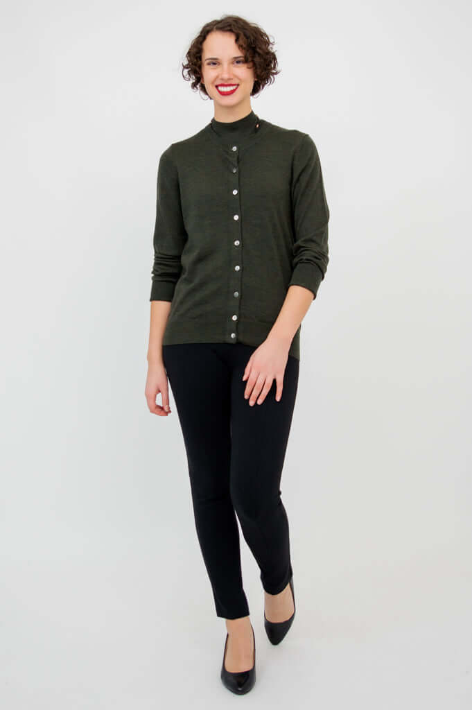 Woman walking forward in a dark green merino wool cardigan and black pants