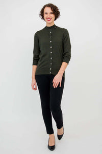 Woman walking forward in a dark green merino wool cardigan and black pants