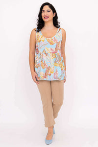 Woman smiling in blue leaf print tank top and beige pants, walking forward