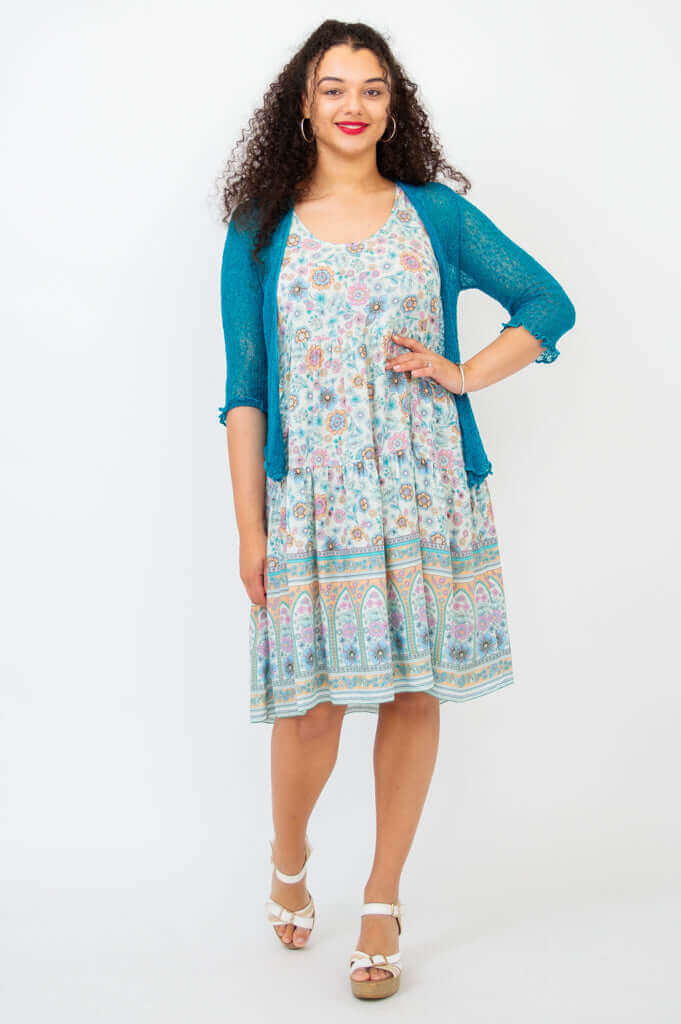 Woman wearing Kayana dress with teal cardigan, smiling forward