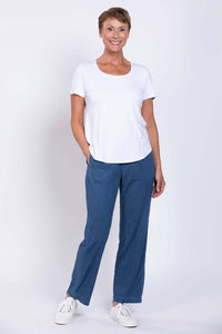 woman posing with hand in pocket smiling in denim pants and white shirt