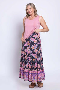 Woman wearing Tibby floral maxi skirt and pink tank top, showing elastic waistband