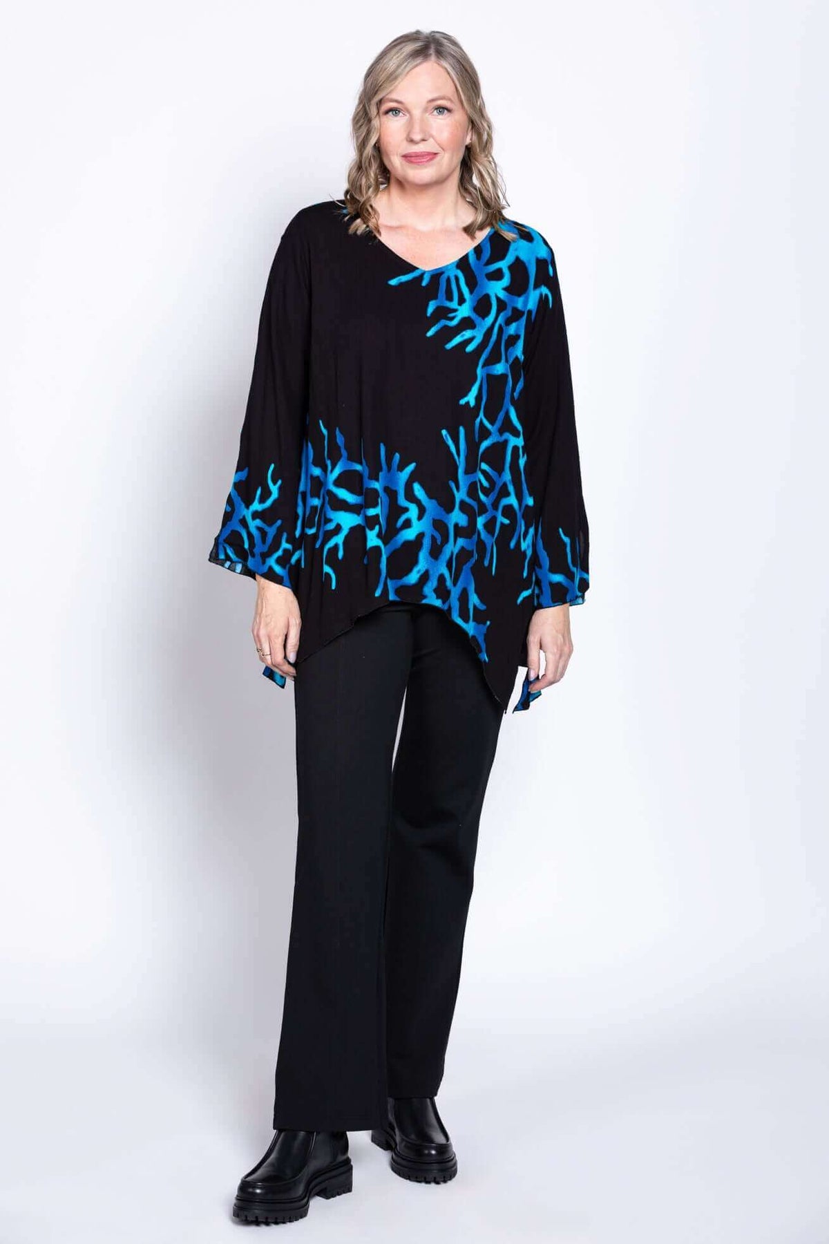 Woman wearing a black top with blue coral patterns and black pants, full body view