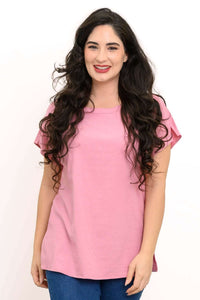 Woman wearing a blush pink tee with dolman cap sleeves and blue jeans, front view