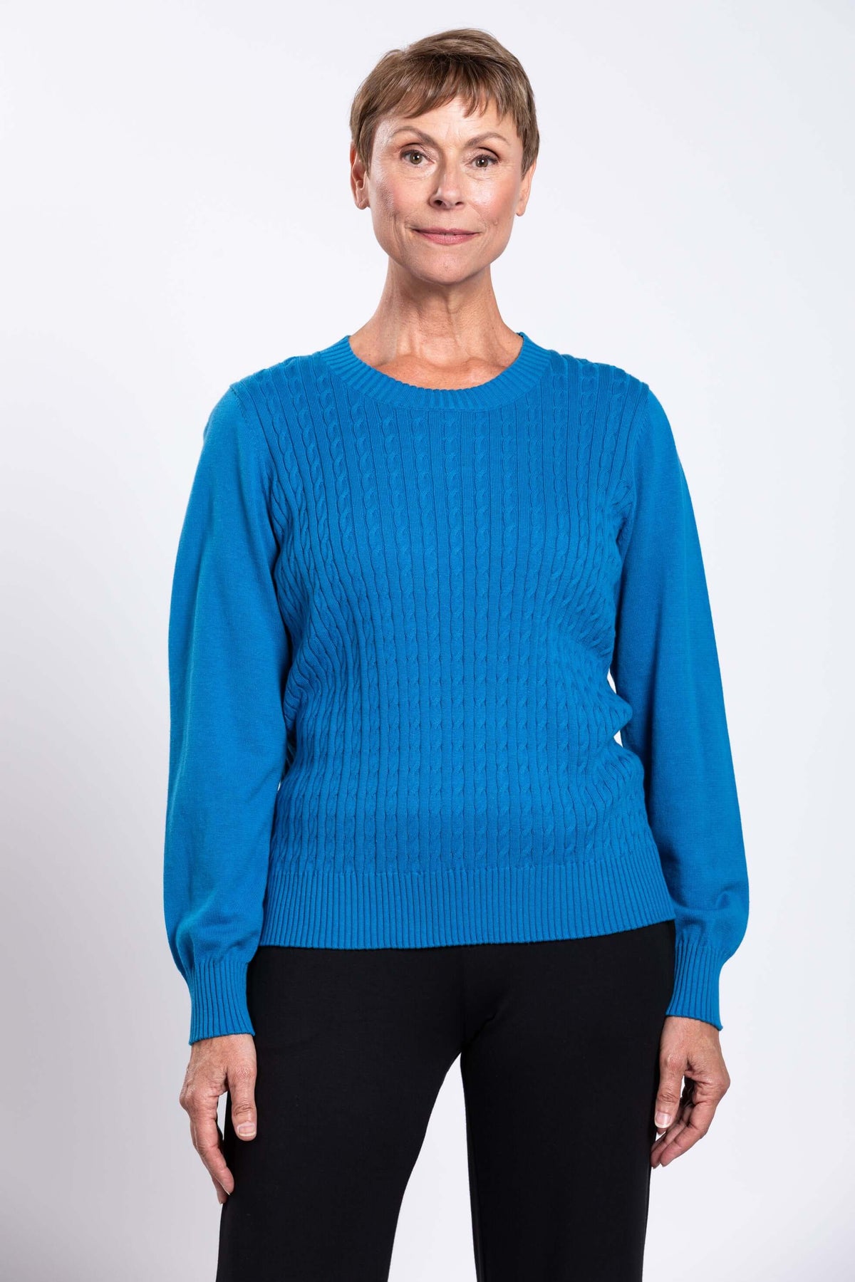 Woman wearing a bright blue cable knit crew neck sweater