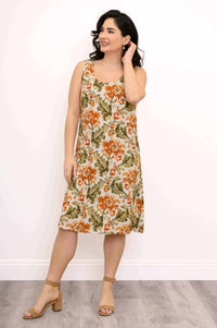 Woman wearing a knee-length sleeveless floral dress with tan block heel sandals