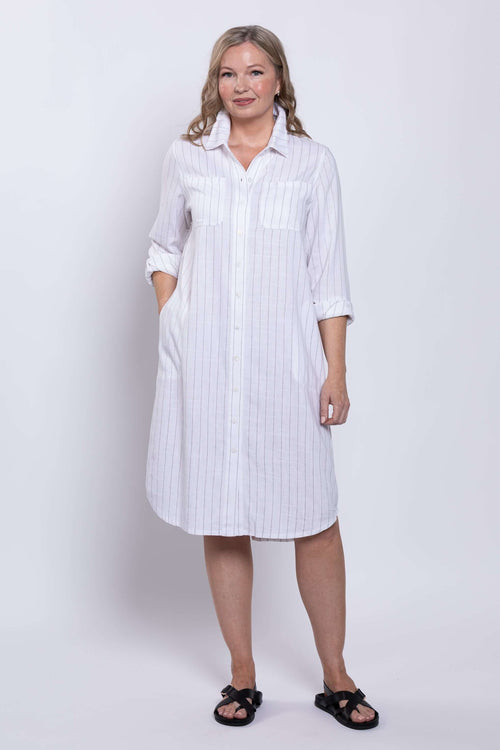 Woman wearing a knee-length white striped shirt dress with rolled sleeves
