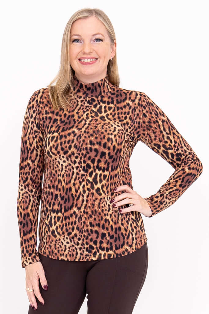Woman wearing a long-sleeve leopard print mock neck top standing and smiling