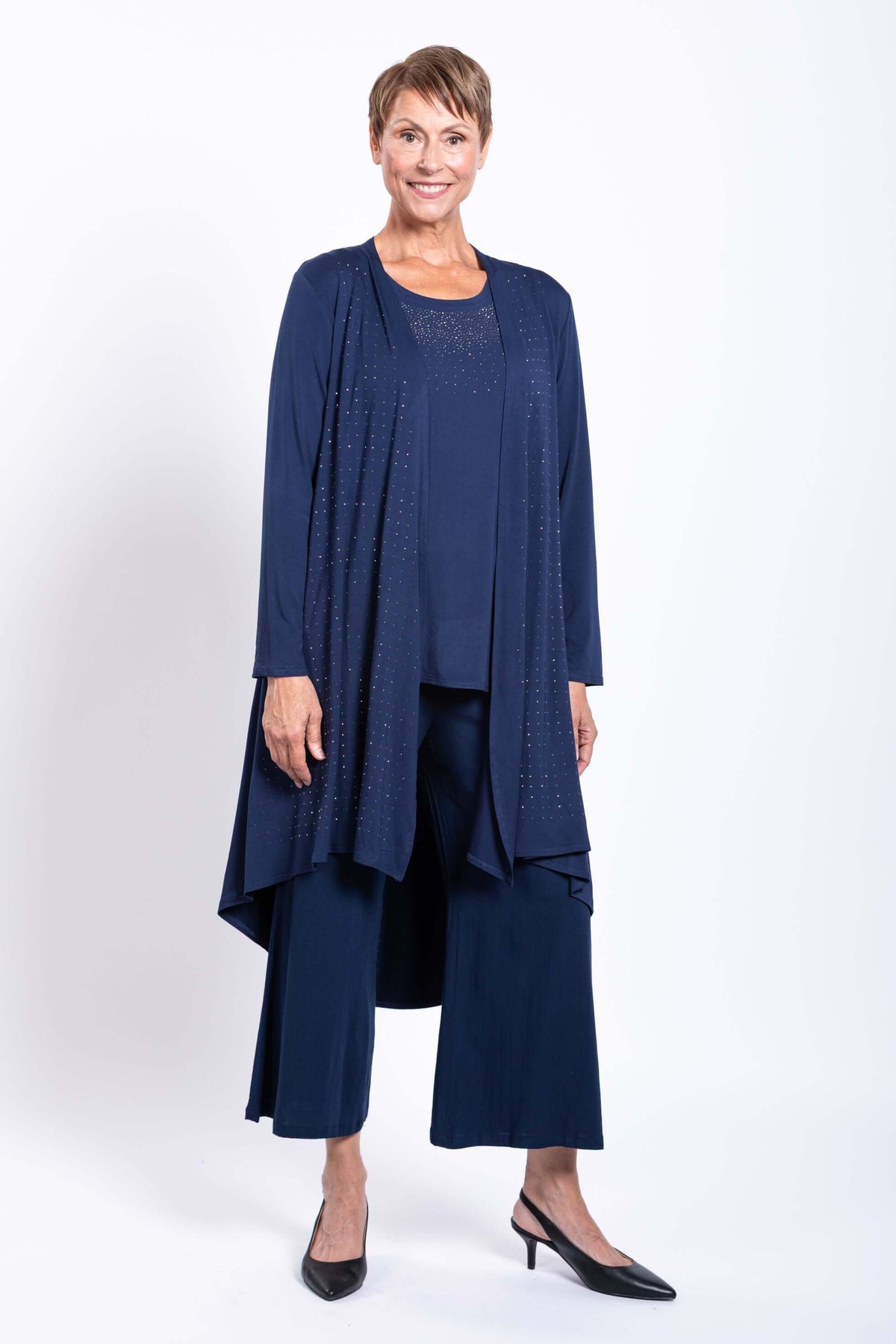 Woman wearing a navy blue duster with subtle embellishments and wide leg pants