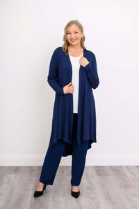 Woman wearing a navy blue high-low duster cardigan over a white top and navy pants