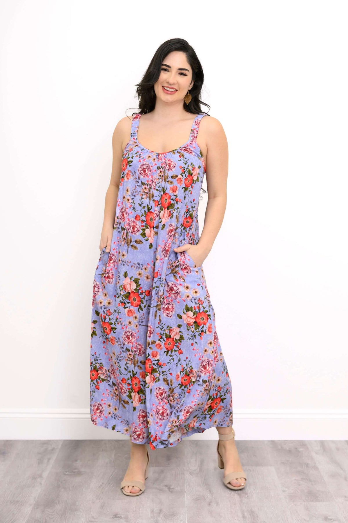 Woman in a sleeveless purple floral jumpsuit with pockets, smiling