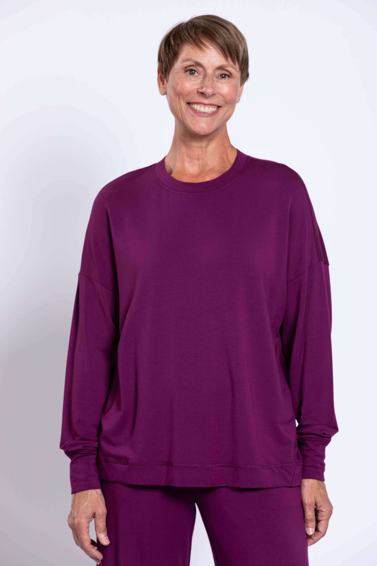 Woman wearing a relaxed-fit purple crew neck top with drop shoulders and long sleeves