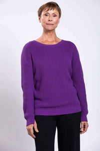 Woman wearing a relaxed fit purple shaker stitch cotton sweater with black pants