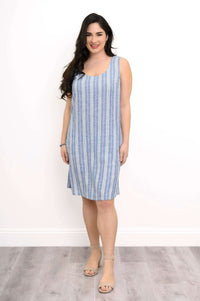 Woman wearing a sleeveless blue and white striped shift dress, standing and smiling