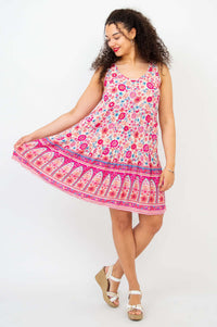 Woman wearing a sleeveless pink and floral tiered dress with a wide hem