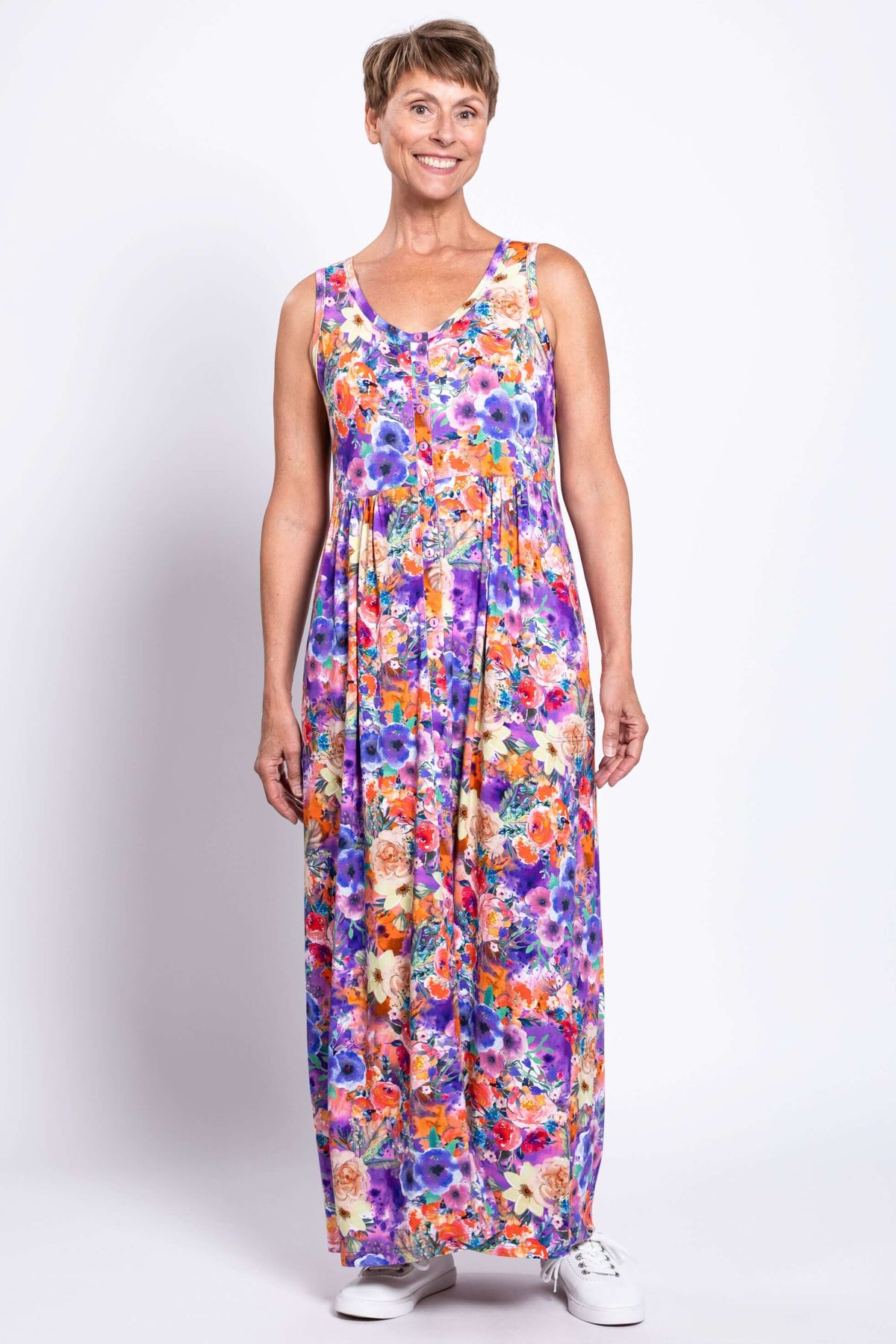 Woman in a vibrant purple and orange floral maxi dress, standing front facing