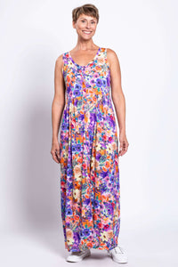 Woman in a vibrant purple and orange floral maxi dress, standing front facing
