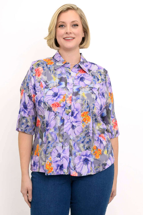 Woman wearing a vibrant purple floral blouse with short sleeves and button front