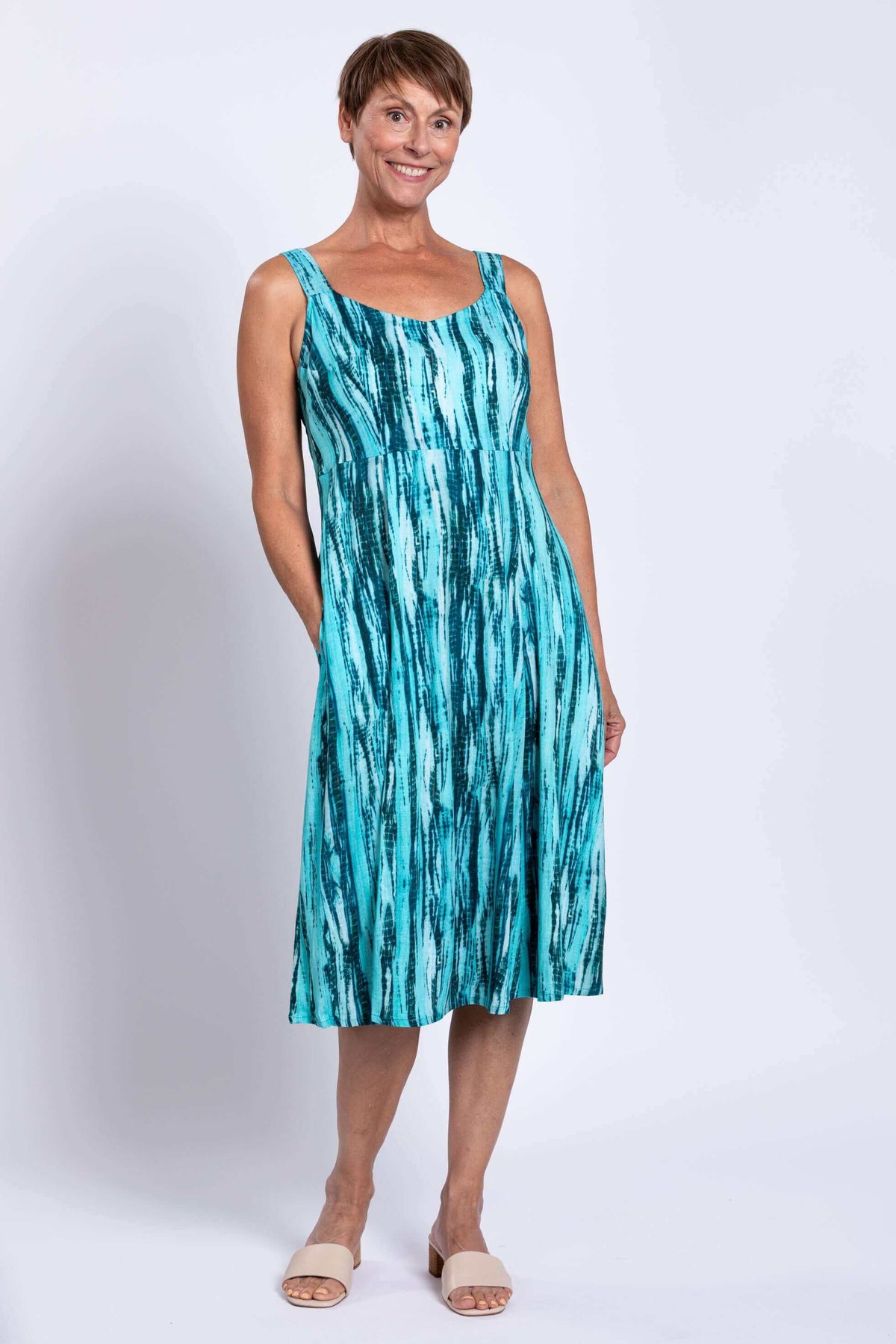 Woman wearing a sleeveless aqua streak print dress with empire waist and pockets