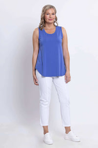 Woman modeling an azure blue sleeveless tank top with a relaxed fit, white pants, and sneakers