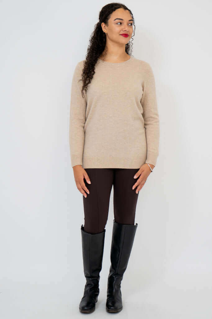 Woman wearing beige sweater looking to the side, full body
