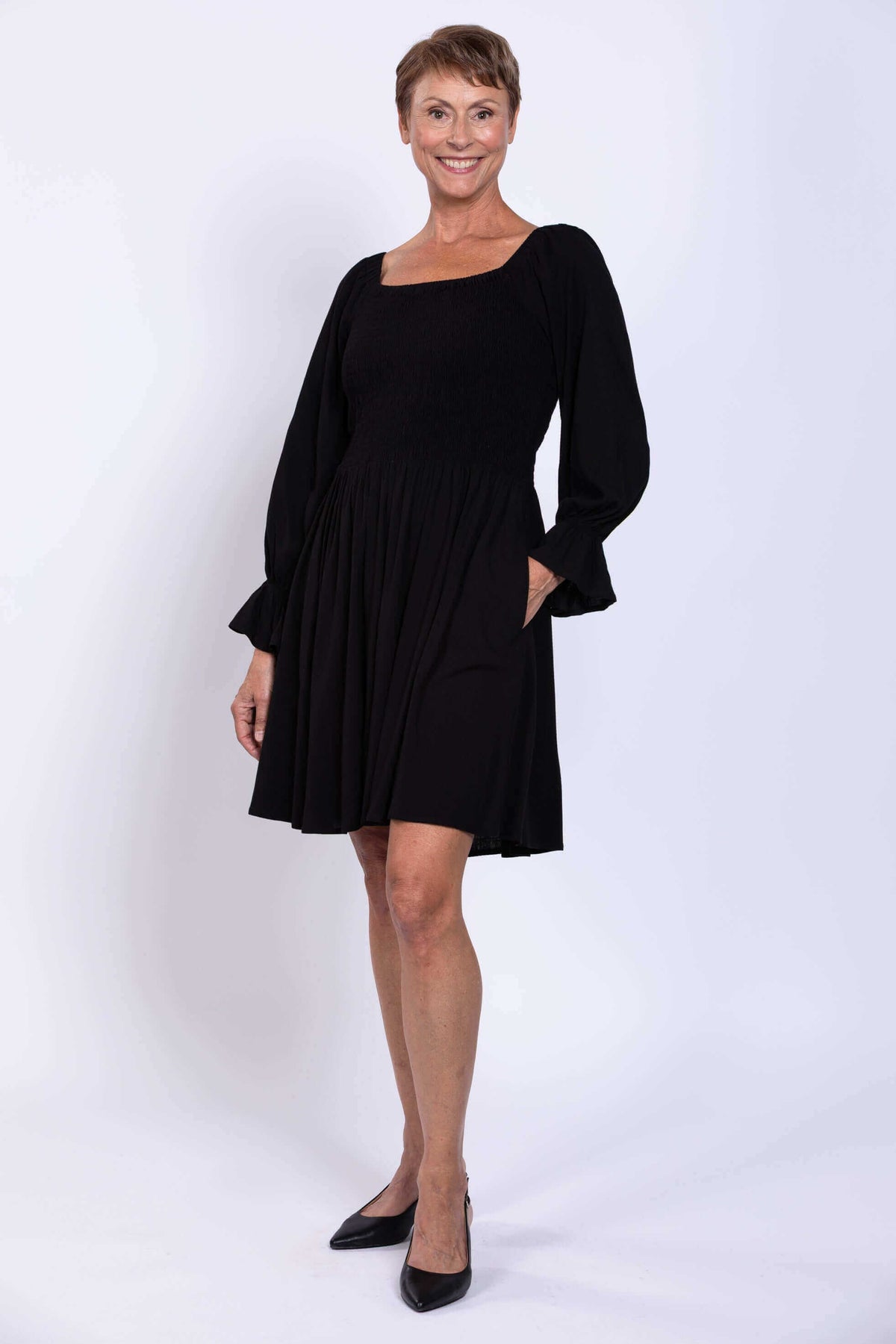 Woman wearing a black Eden dress with long ruffled sleeves and square neckline