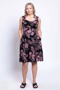 Woman wearing black and pink floral A-line dress with hands in pockets