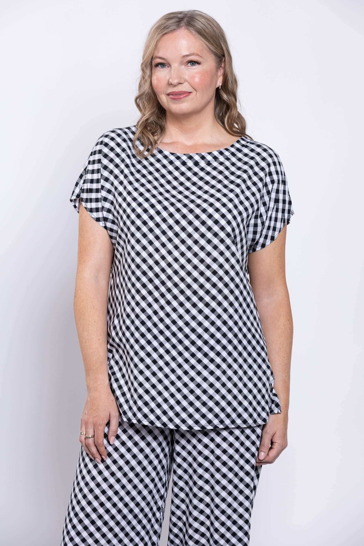 Woman wearing a black and white gingham short-sleeve dolman style tee and matching pants