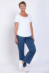 Woman wearing blue tencel denim pants and white t-shirt, standing and smiling