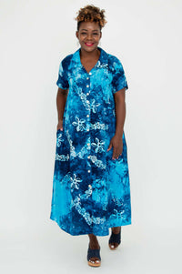 Woman wearing blue batik A-line dress, facing forward and smiling