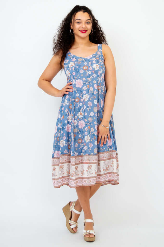 Woman wearing a sleeveless blue floral midi dress with an A-line skirt