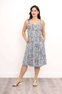 Woman wearing a sleeveless, blue paisley knee-length dress with pockets