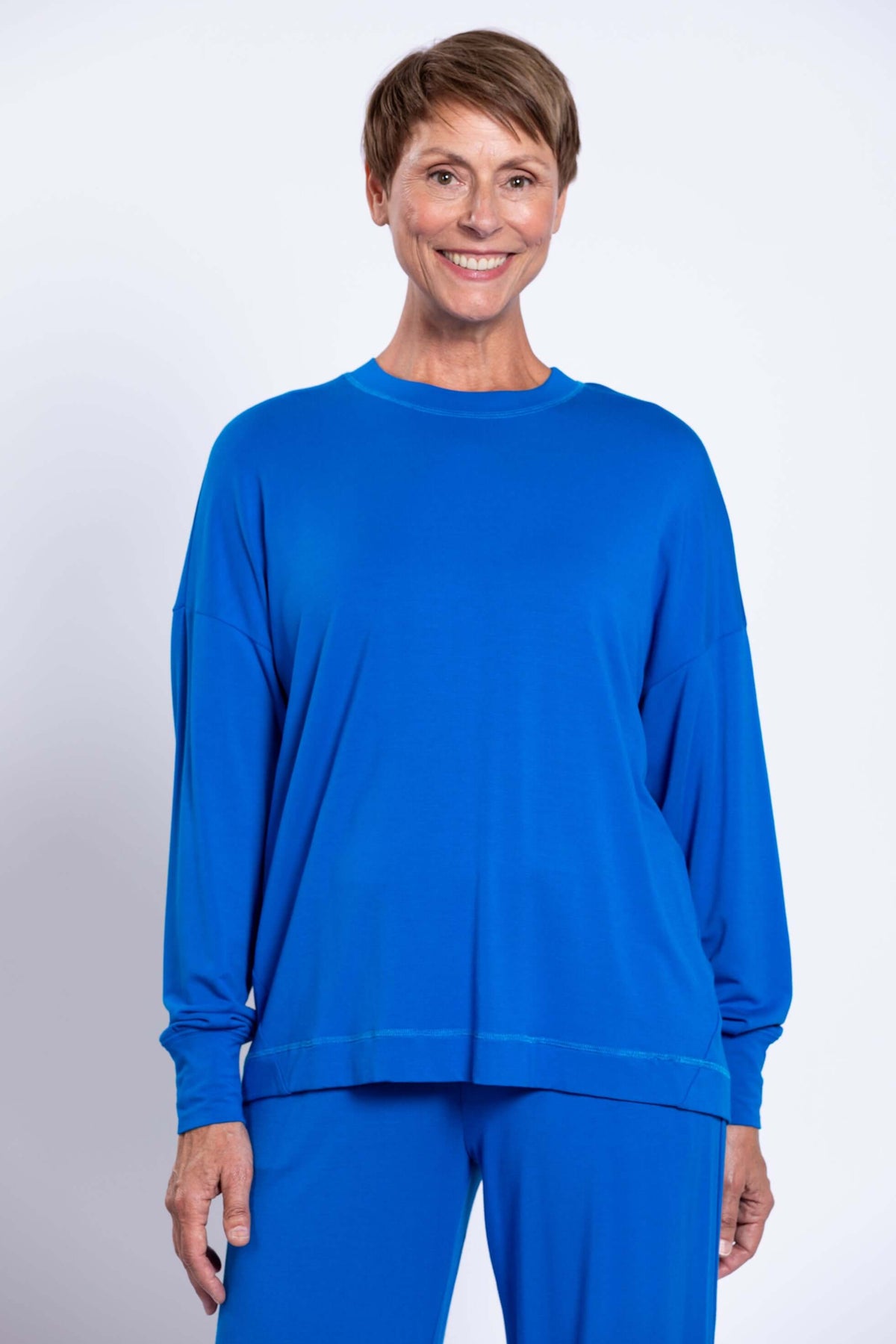Woman in bright blue relaxed crew neck top with drop shoulder and full sleeves