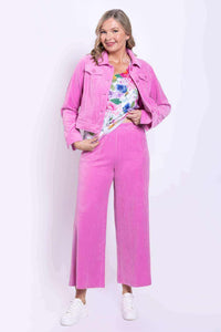 Woman wearing bright pink wide-leg corduroy pants with matching jacket and floral top