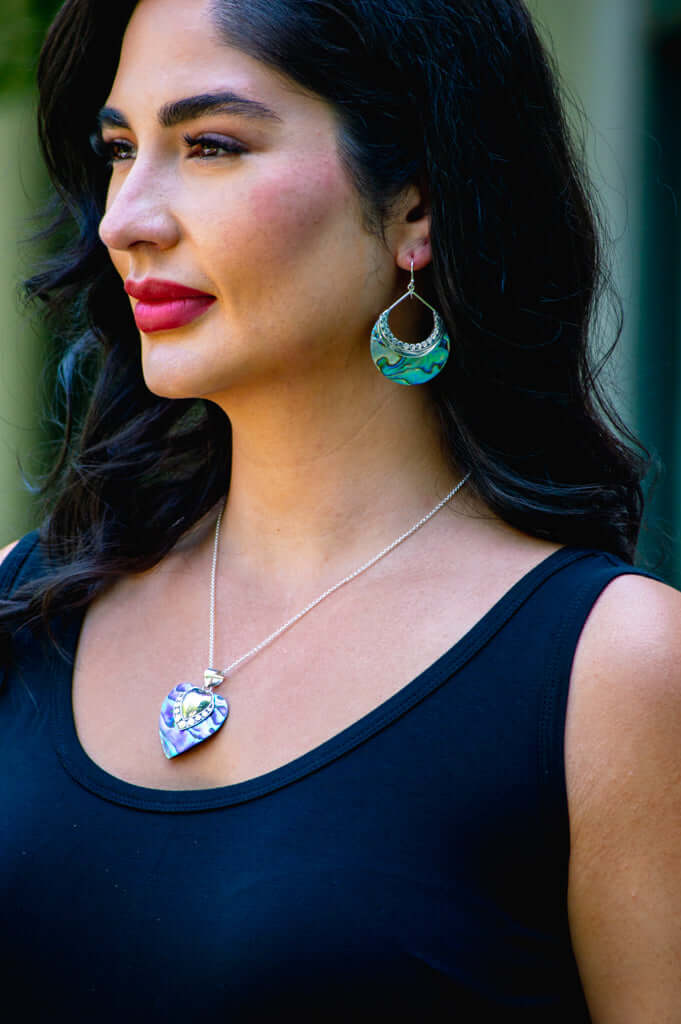 Woman wearing iridescent heart pendant necklace and matching earrings