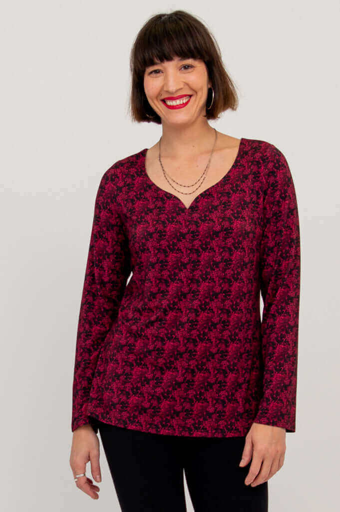Woman modeling maroon floral long sleeve top with sweetheart neckline, arms relaxed