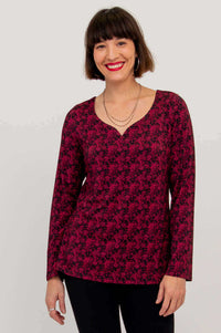 Woman modeling maroon floral long sleeve top with sweetheart neckline, arms relaxed