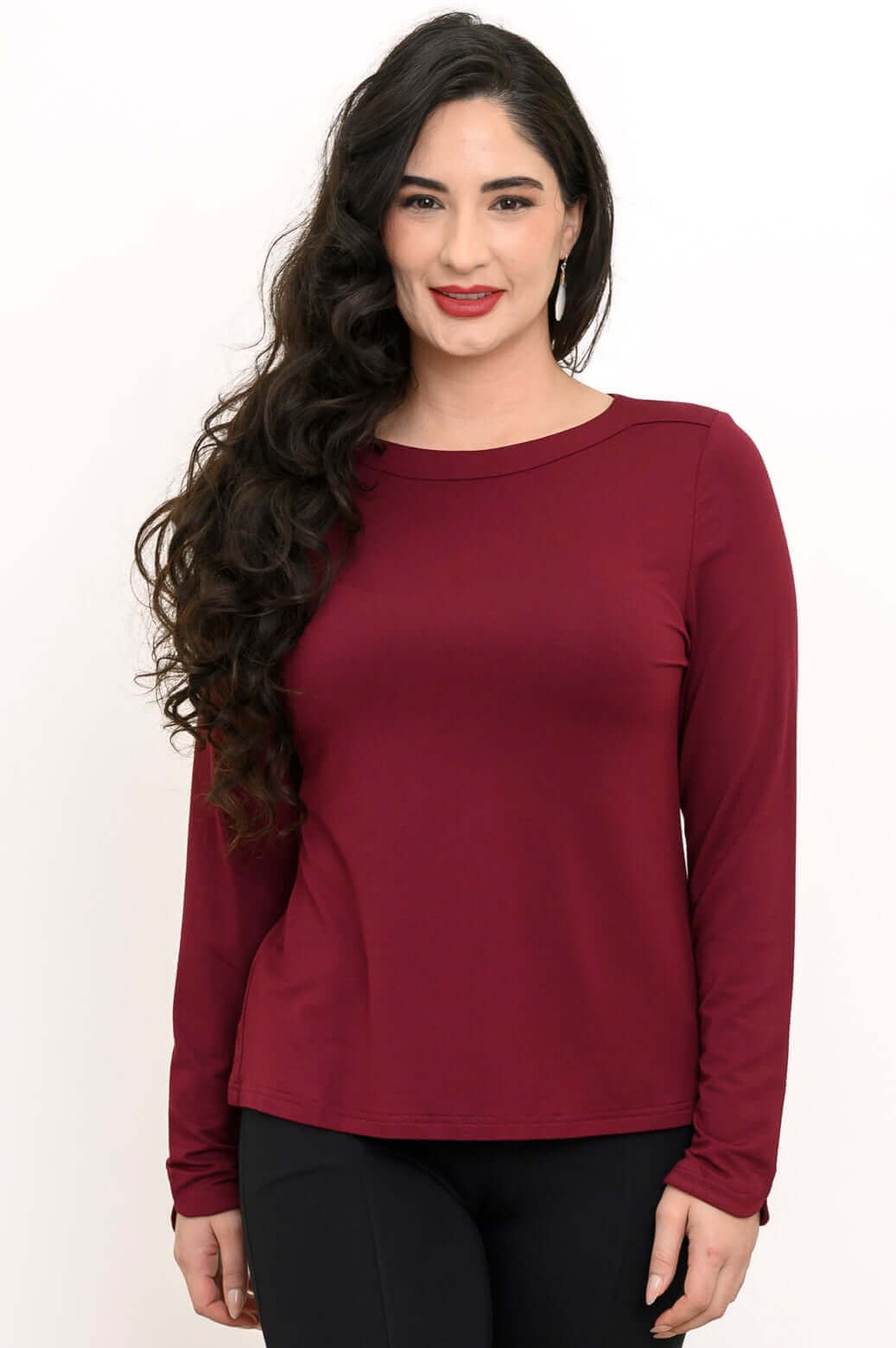 Woman wearing a long sleeve merlot boat neck top with black pants