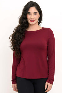 Woman wearing a long sleeve merlot boat neck top with black pants