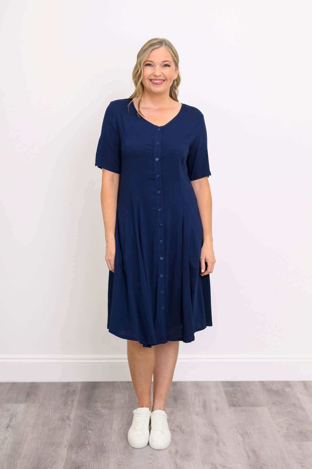 Woman wearing navy blue button-front midi dress with short sleeves and white sneakers