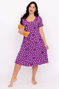 Woman wearing purple dot sleepshirt smiling and holding a teddy bear