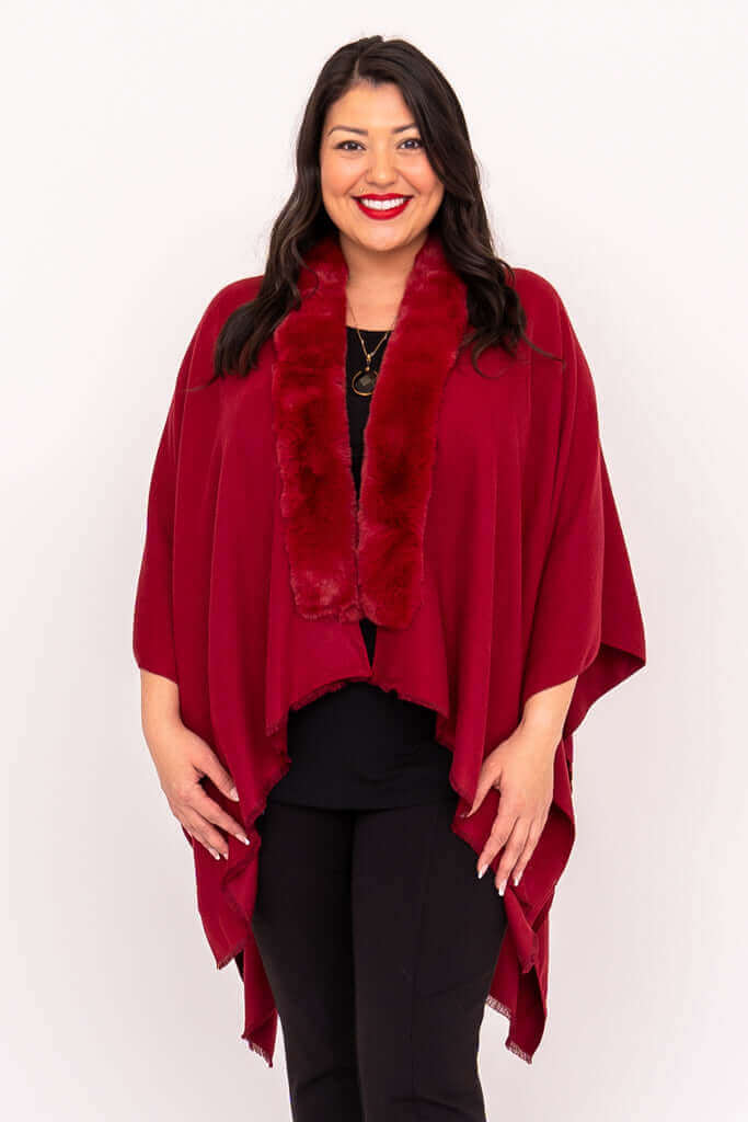 Woman wearing a scarlet wrap with faux fur collar, standing and smiling