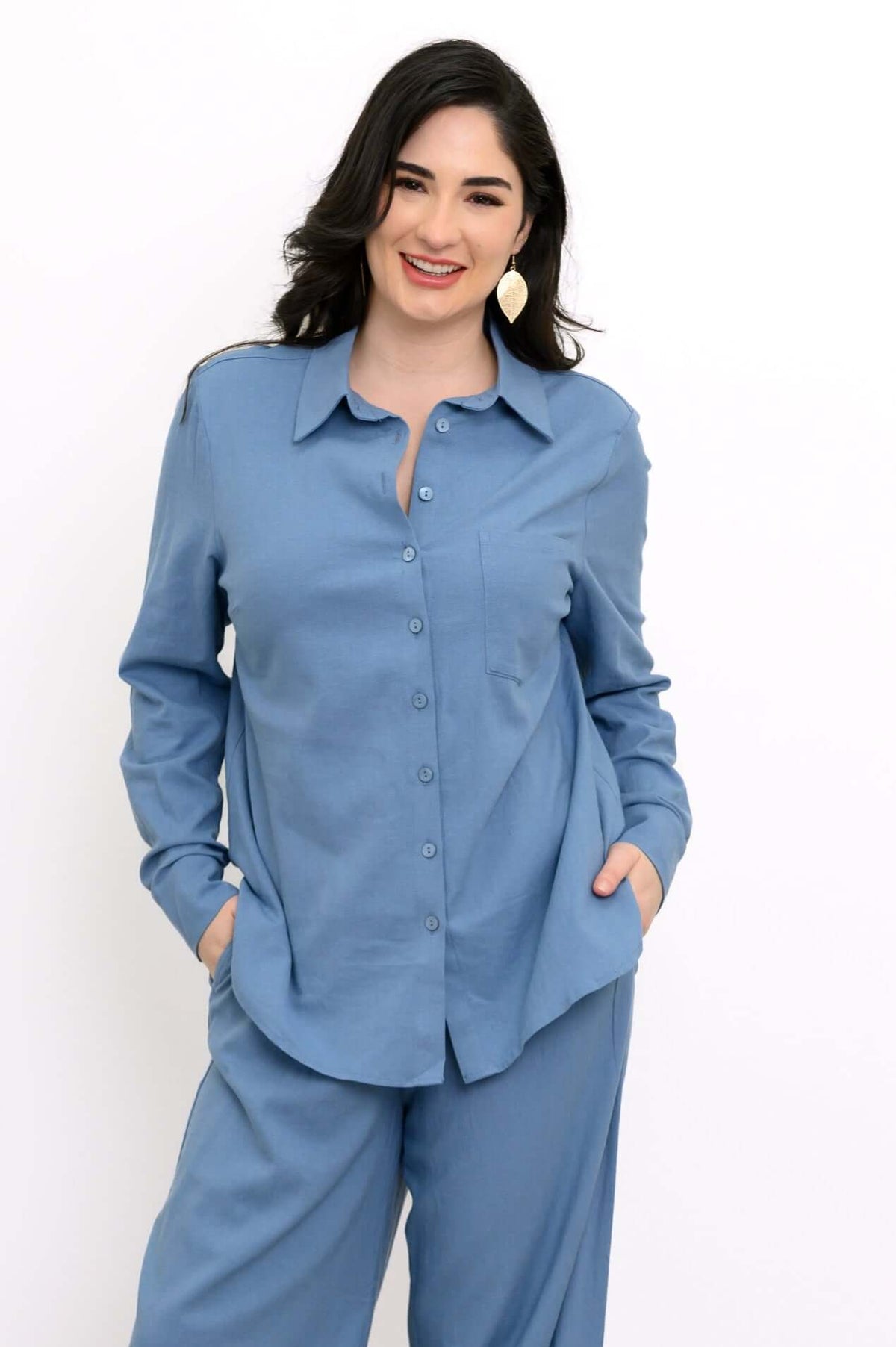 Woman wearing a sky blue long sleeve shirt and pants with hands in pockets