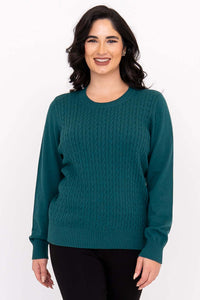 Woman wearing a teal cable knit crew neck sweater with ribbed cuffs, front view